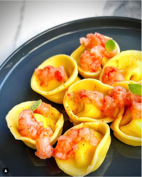 Tortelli aromatizzati al limone, con gamberi, datterini e gamberi rossi in polvere