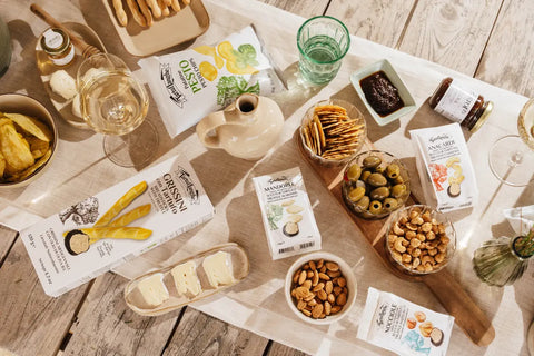 Tavola da aperitivo con patatine, grissini, frutta secca, olive, formaggi e snack Tartuflanghe al tartufo.