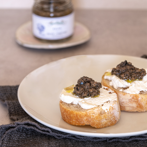 Crostini con formaggio cremoso e salsa di olive e tartufo, serviti su un piatto.