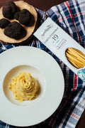 TARTUFISSIMA_N_19_TAGLIATELLE all'uovo con tartfo nero in piatto bianco, su tovaglia blu a quadri