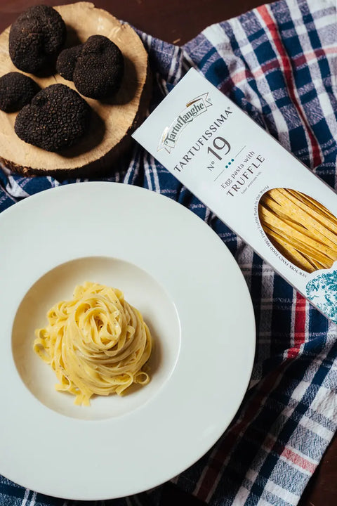 TARTUFISSIMA_N_19_TAGLIATELLE all'uovo con tartfo nero in piatto bianco, su tovaglia blu a quadri