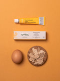 Tubetto e confezione di Truffleggs Tartuflanghe, crema di tuorlo d’uovo e tartufo bianco da 27 g, con un uovo e lamelle di tartufo su fondo arancione