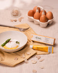 Uovo in camicia con asparagi e crema Truffleggs al tuorlo d’uovo e tartufo bianco, accanto al tubetto e alla confezione Tartuflanghe